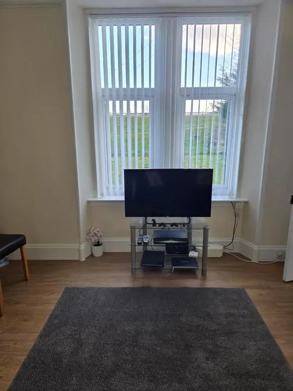 a living room with a flat screen tv in front of a window at Ardgay in Fort Augustus