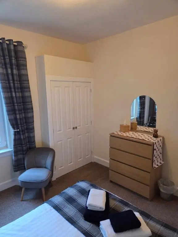 a bedroom with a bed and a mirror and a chair at Ardgay in Fort Augustus