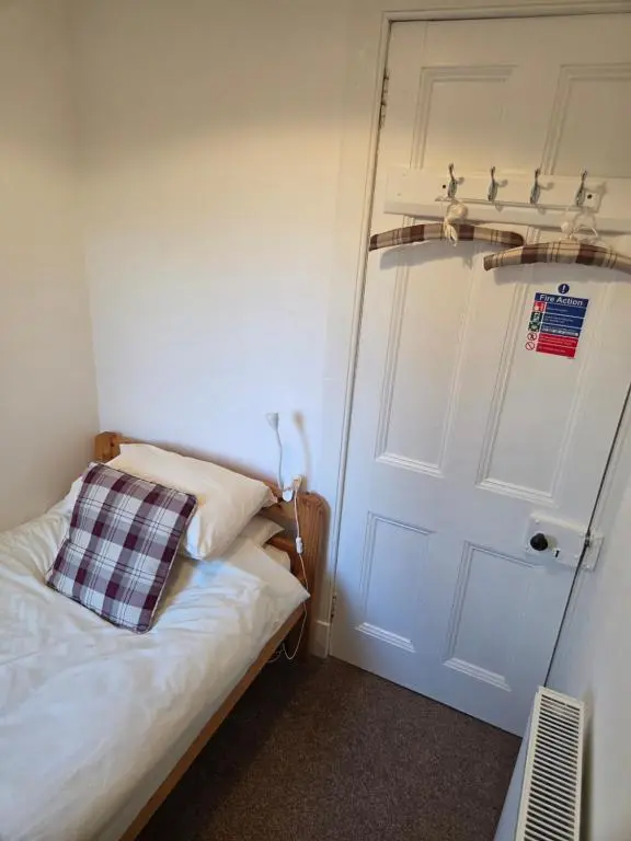 a small bedroom with a bed and a white door at Ardgay in Fort Augustus