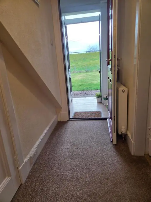 an empty hallway with an open door to a field at Ardgay in Fort Augustus