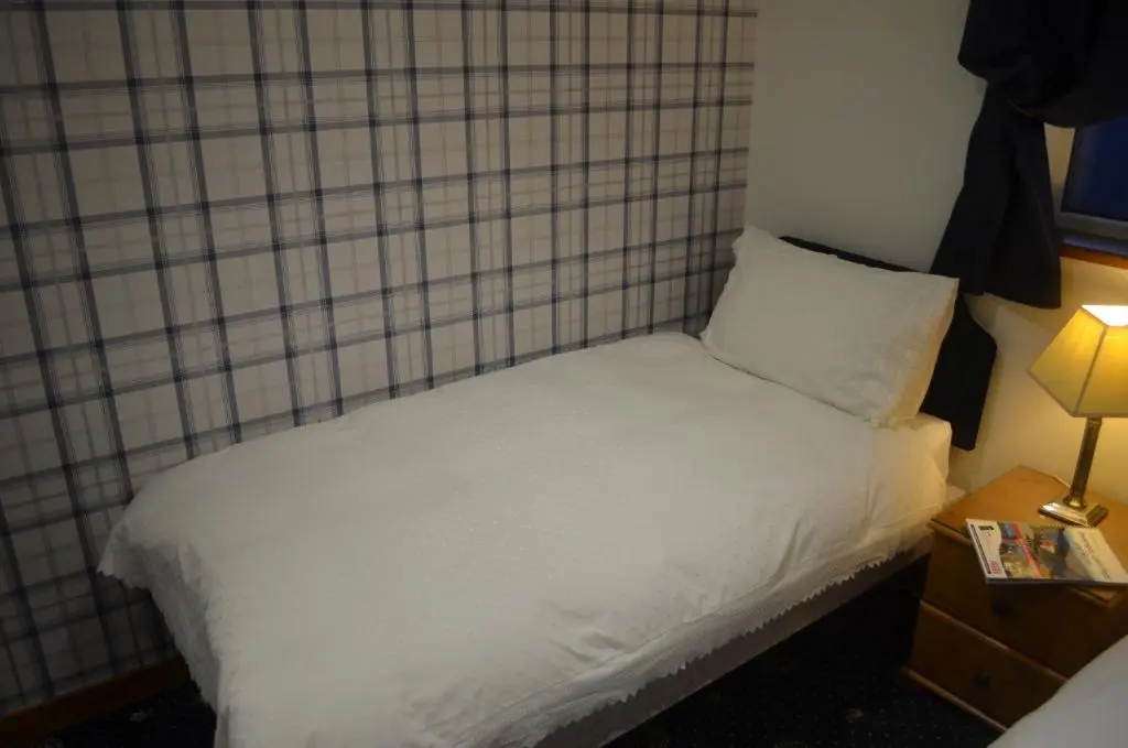 a small bed with white sheets and a night stand at Roseneath Guest House in Inverness