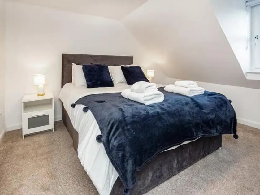 a bedroom with a large bed with towels on it at 4 Lower Kessock Street in Inverness