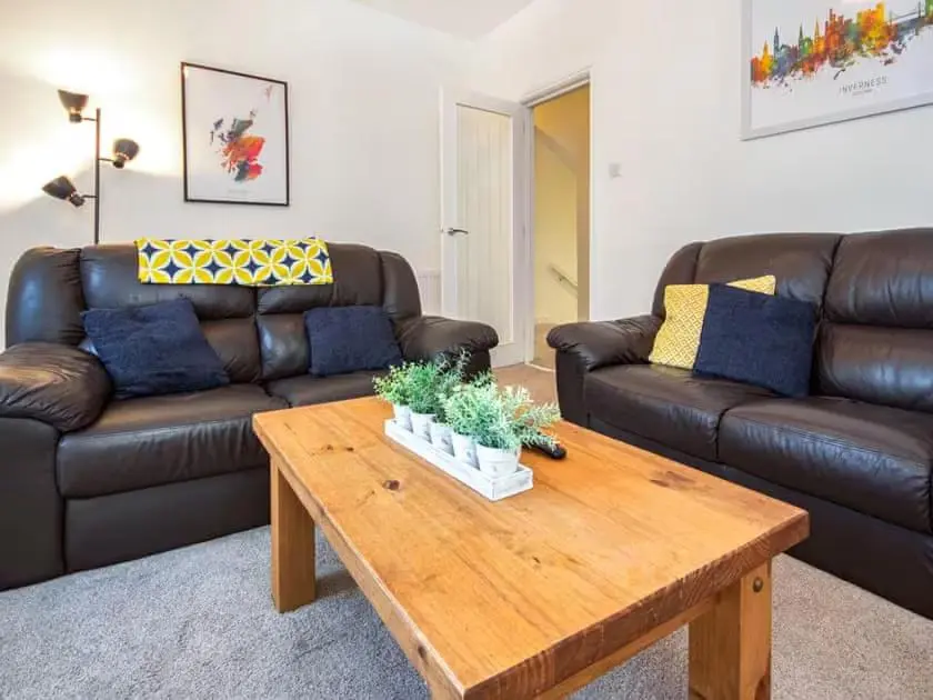 a living room with a leather couch and a coffee table at 4 Lower Kessock Street in Inverness