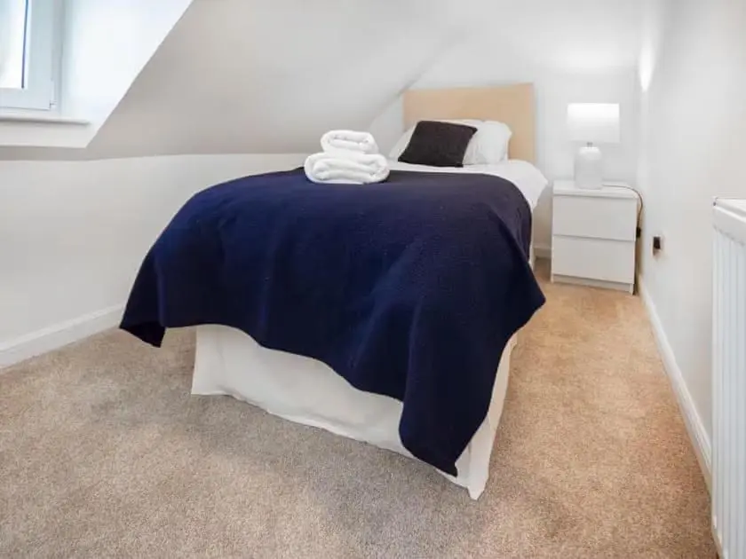 a bedroom with a bed with a blue and white blanket at 4 Lower Kessock Street in Inverness