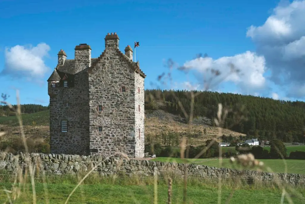 an old stone building in a field with a stone wall at Forter Castle in Blairgowrie