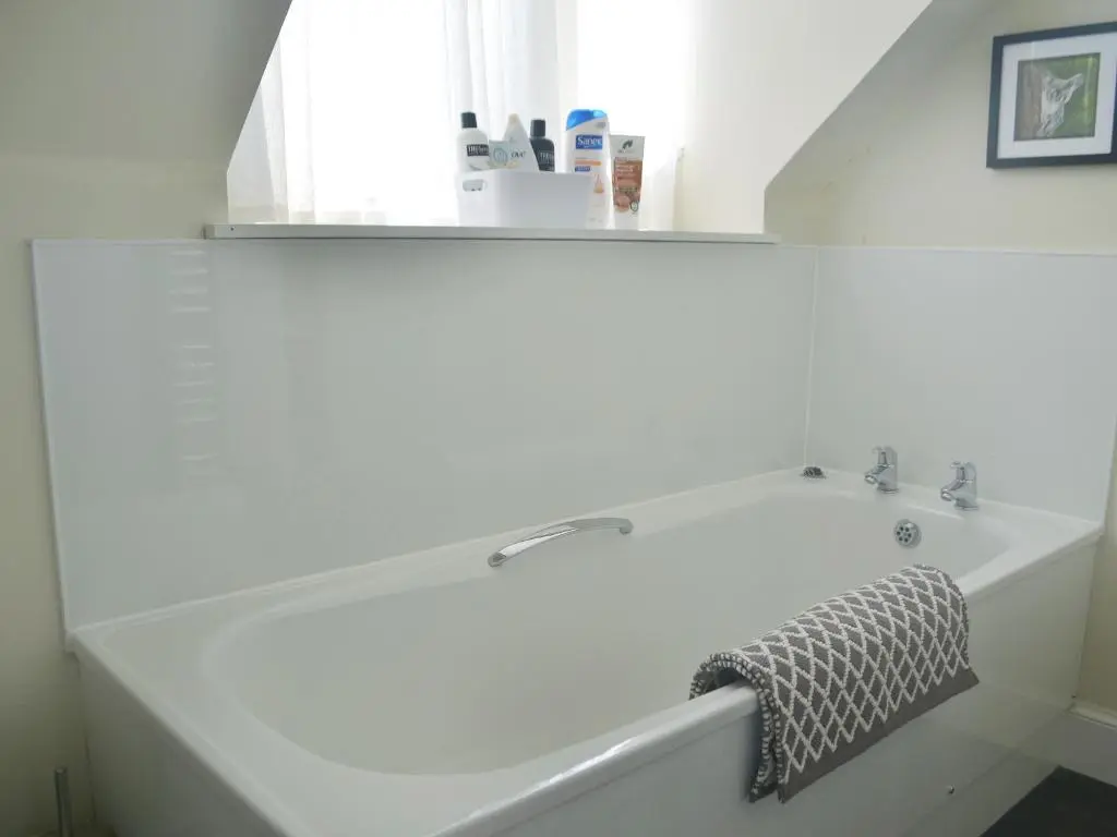 a white bath tub in a white bathroom with a towel at Dolphin Cottage in Nairn