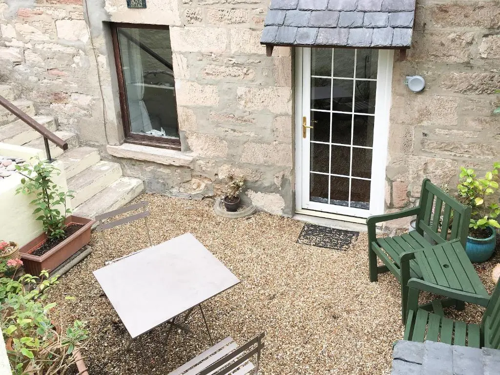 a patio with a green chair and a painting at Dolphin Cottage in Nairn