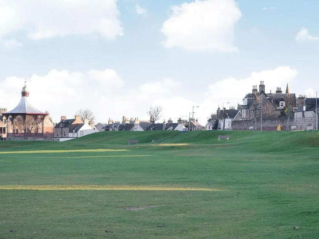a green golf course with a castle in the background at Dolphin Cottage in Nairn