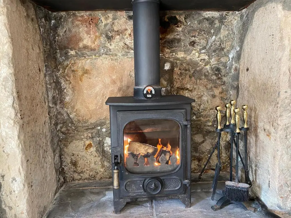 a fireplace in a stone wall with a stove at Dolphin Cottage in Nairn
