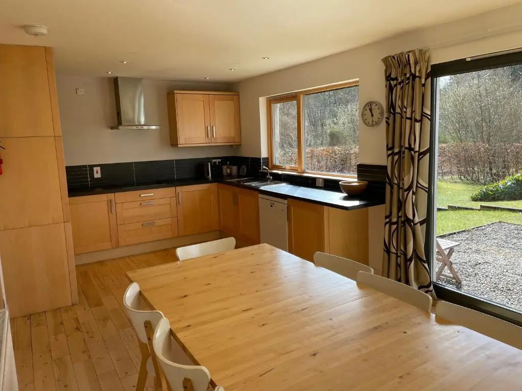 a kitchen with a wooden table and a table and chairs at Bright, contemporary house & large private garden in Strathpeffer