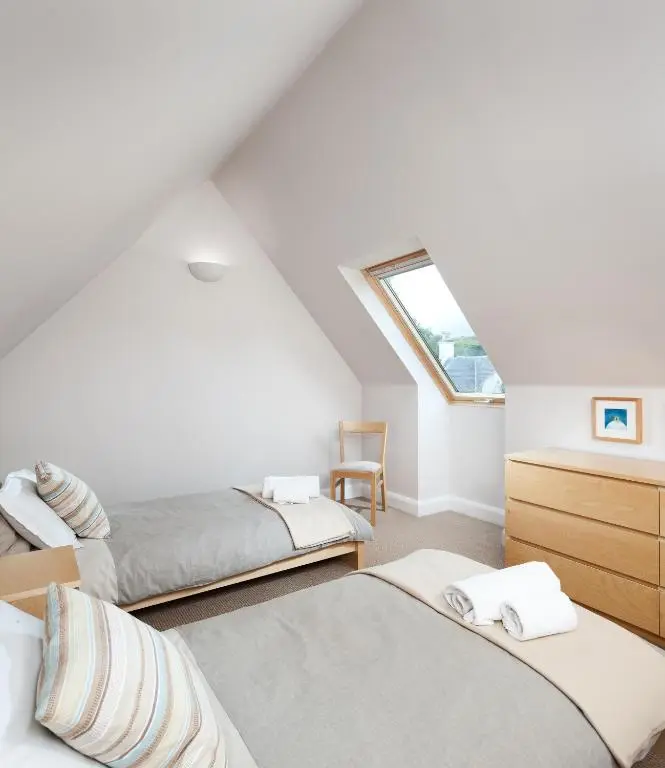 a attic bedroom with three beds and a window at Bright, contemporary house & large private garden in Strathpeffer
