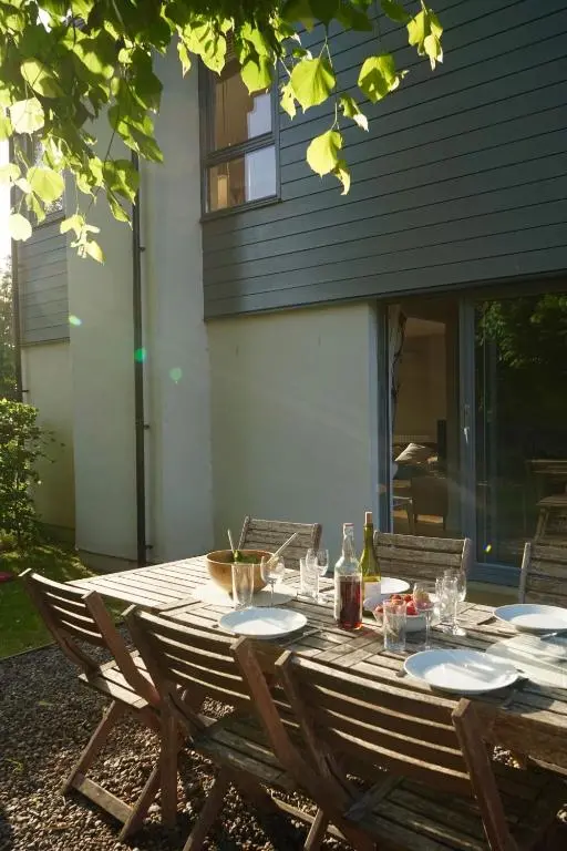 a wooden table with plates and wine glasses on it at Bright, contemporary house & large private garden in Strathpeffer