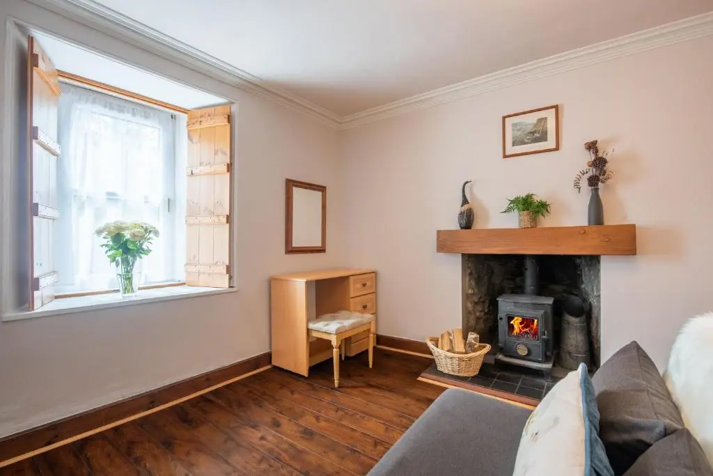 a living room with a fireplace and a couch at Traditional Highland Cottage Near Loch Ness in Drumnadrochit
