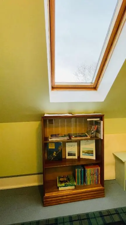 a book shelf in a room with a window at Traditional Highland Cottage Near Loch Ness in Drumnadrochit