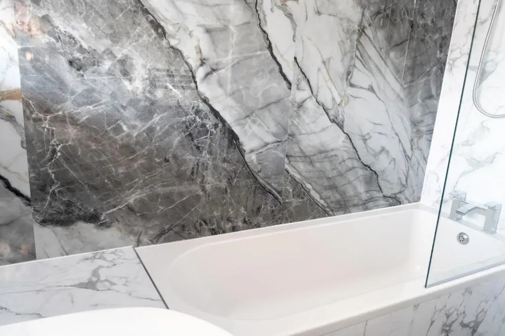 a bathroom with a white tub and a marble wall at Rosewood Cottage in Cornhill