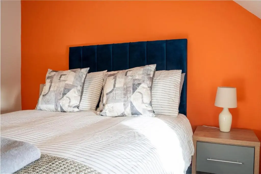 a bedroom with an orange wall and a bed at Rosewood Cottage in Cornhill