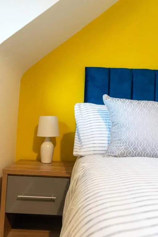 a bedroom with a bed with a blue and yellow wall at Rosewood Cottage in Cornhill