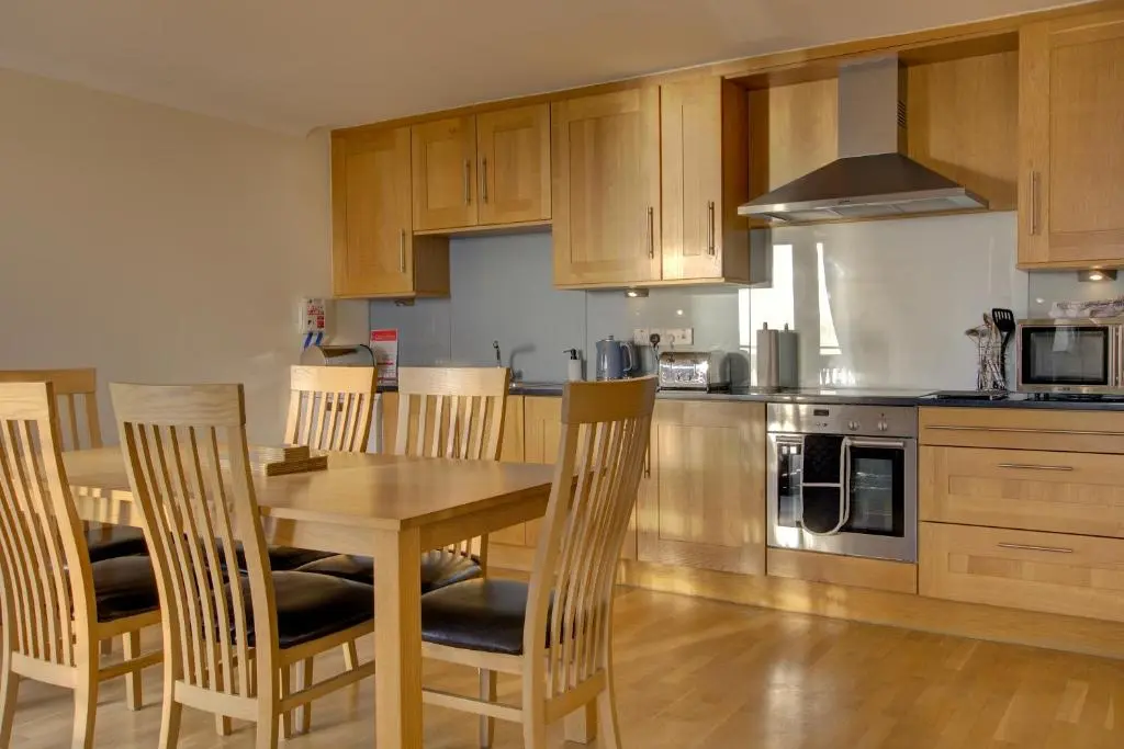 a kitchen with a wooden table and chairs at No10 The Links Apartment, Brora in Brora
