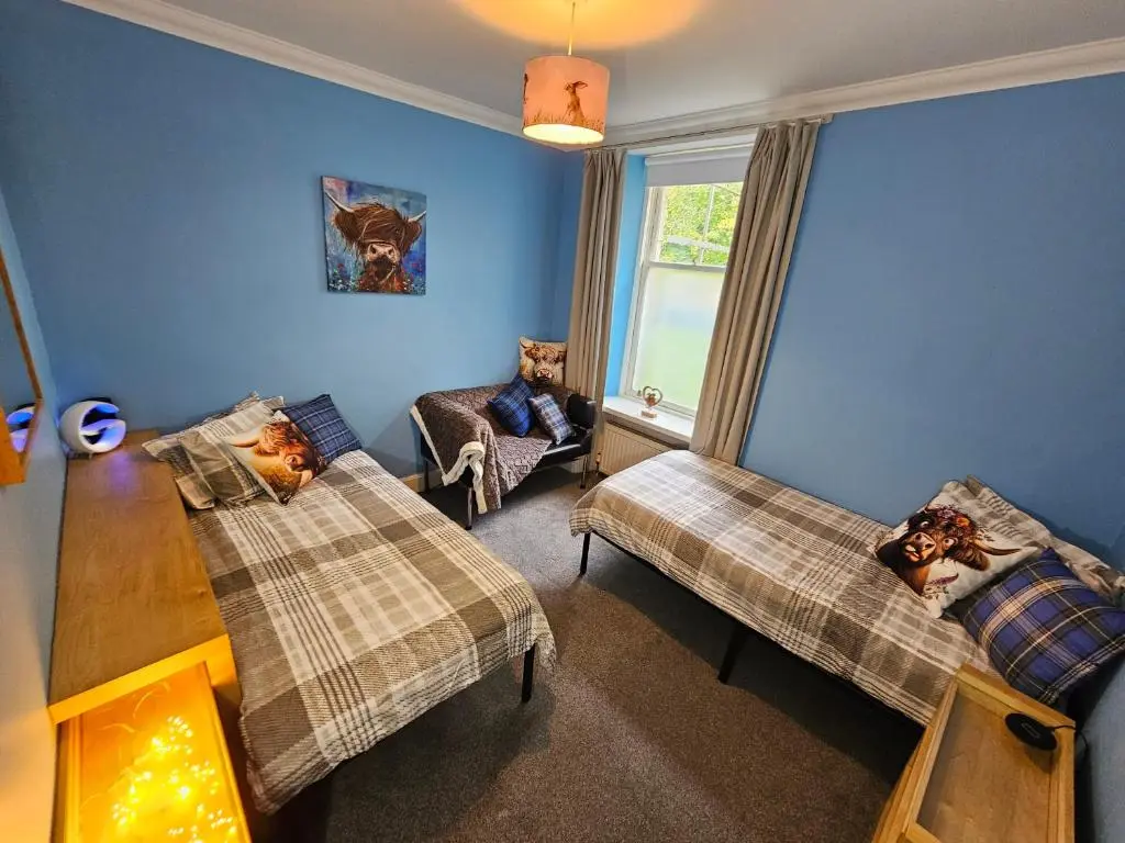 a living room with two beds and a table at Cosy highland getaway in Grantown on Spey