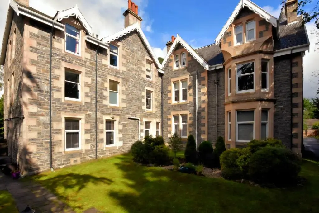 a large stone house with a green yard at Cosy highland getaway in Grantown on Spey