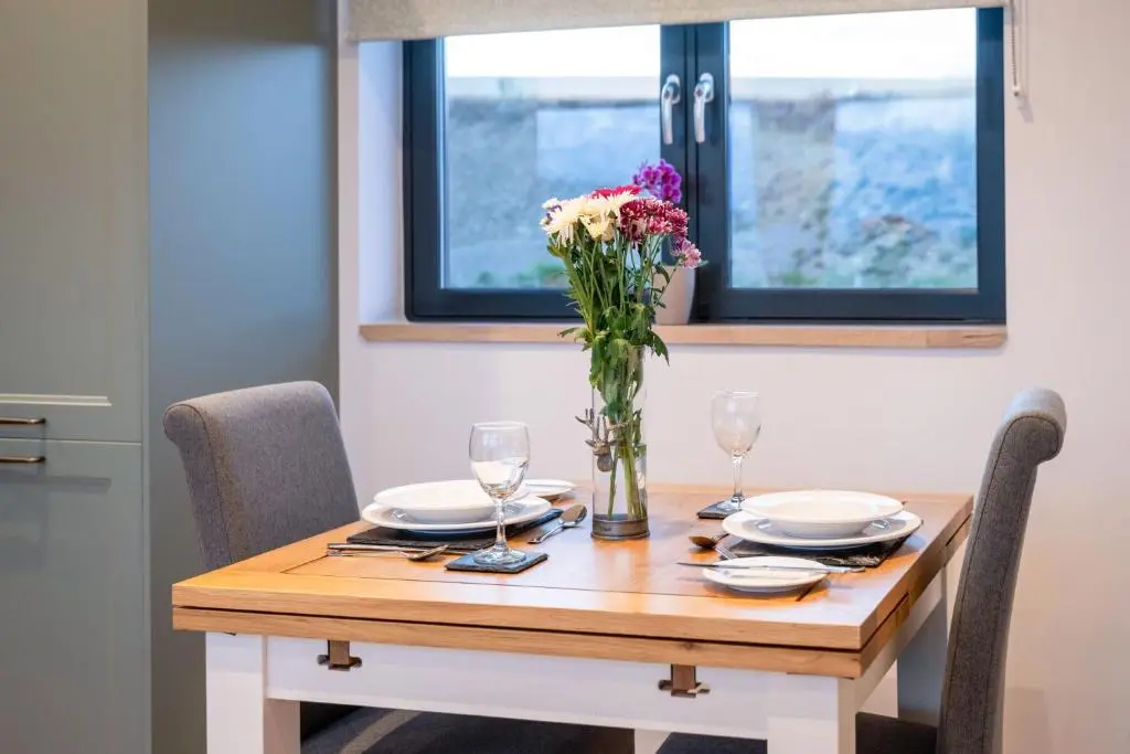 a wooden table with a vase of flowers on it at Bennachie Lodge in Huntly