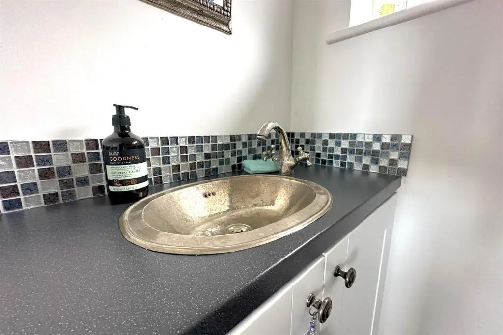 a bathroom counter with a sink with a bottle of wine at The Old Coastguard Station in Helmsdale
