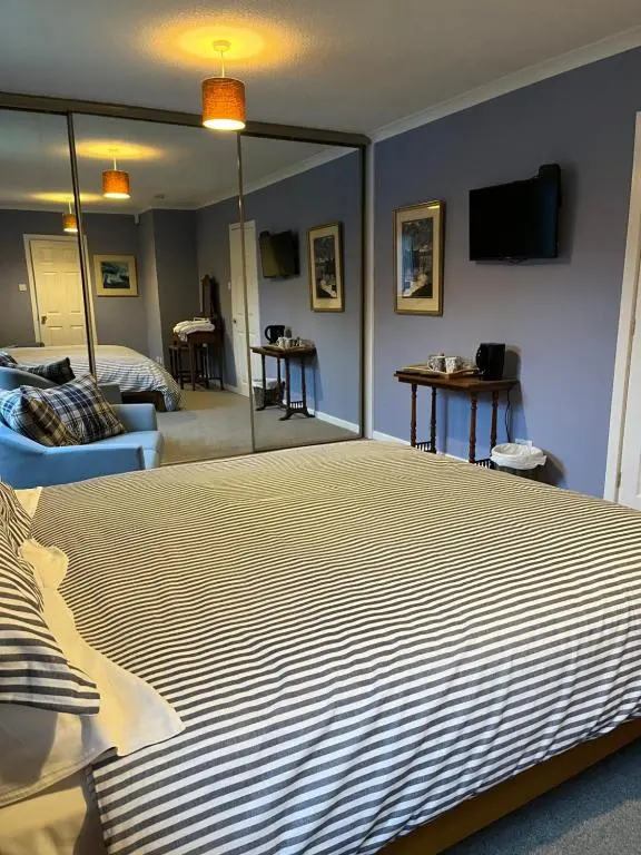 a bedroom with a large bed and a mirror at Runnymede House in Inverness