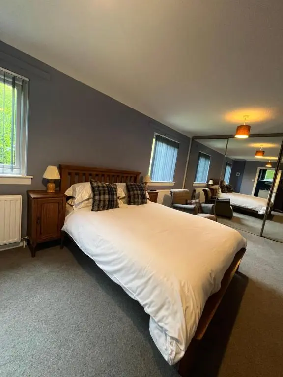a bedroom with a large bed and a living room at Runnymede House in Inverness