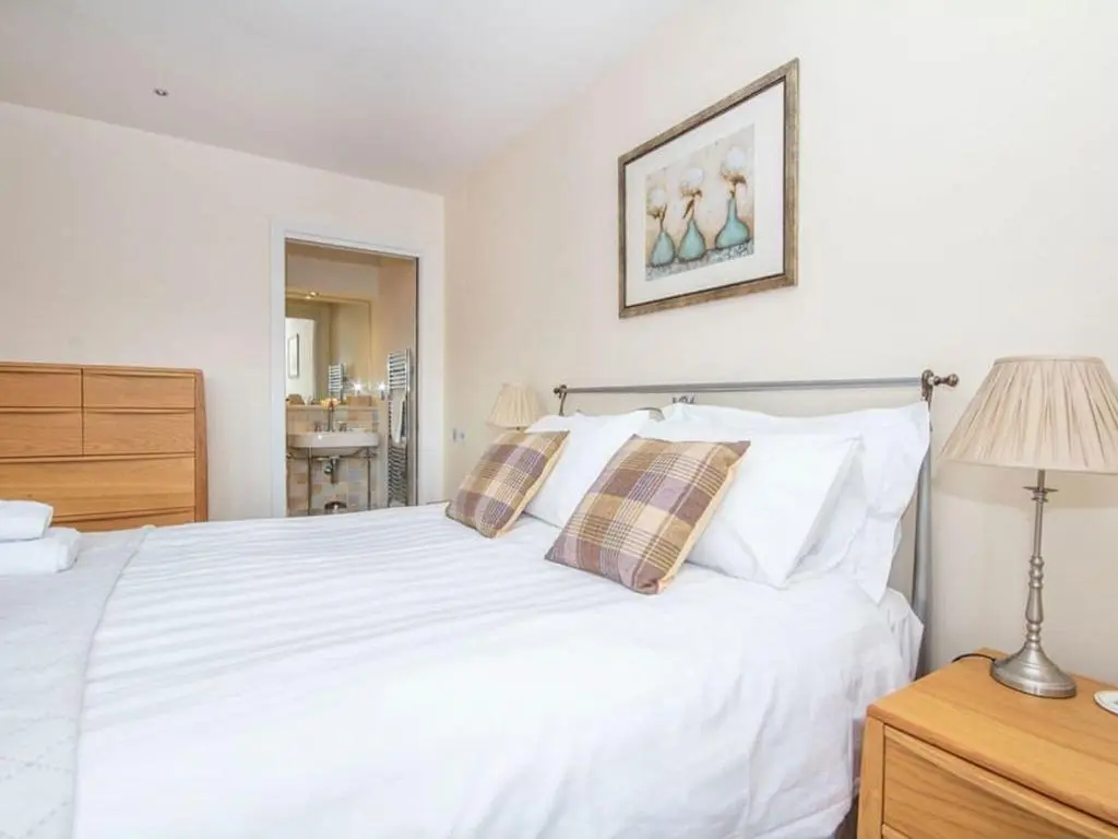 a bedroom with a white bed with pillows and a lamp at 2 Bedroom Riverside Apartment 301-Free Parking in Inverness