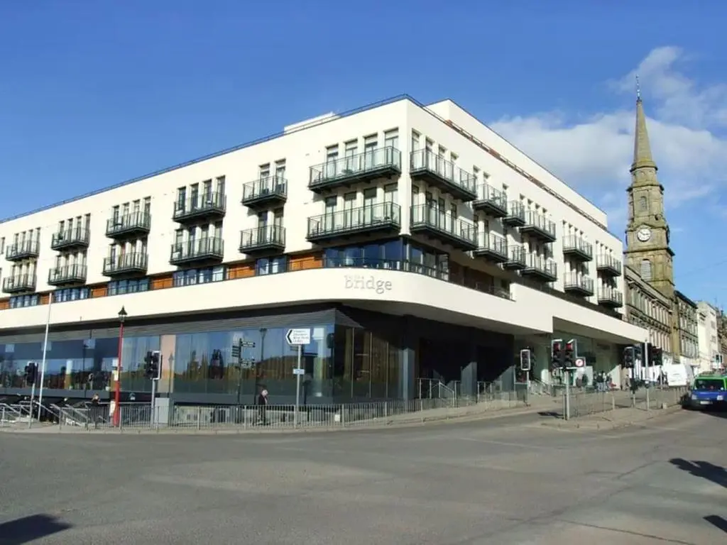 a large white building with a clock tower on a street at 2 Bedroom Riverside Apartment 301-Free Parking in Inverness