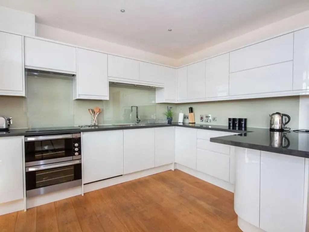 a kitchen with white cabinets and black counter tops at 2 Bedroom Riverside Apartment 301-Free Parking in Inverness
