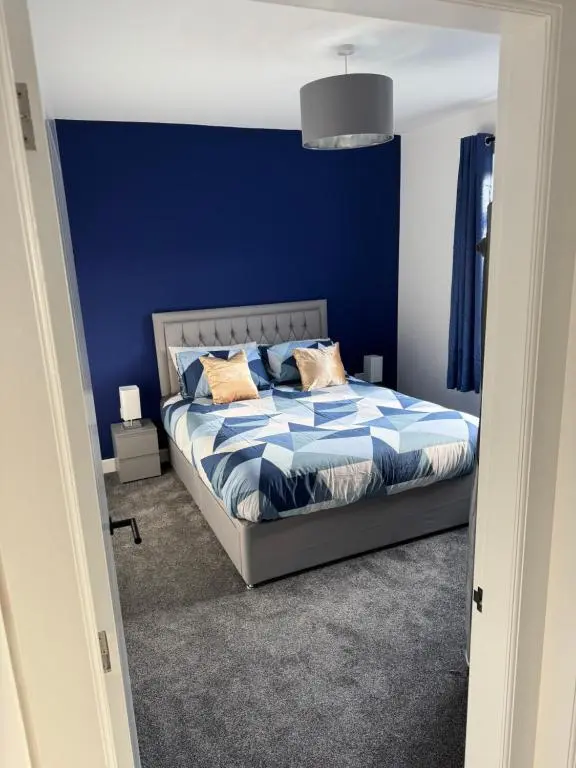 a bedroom with a bed with a blue wall at Lorna Doune in Port Elphinstone