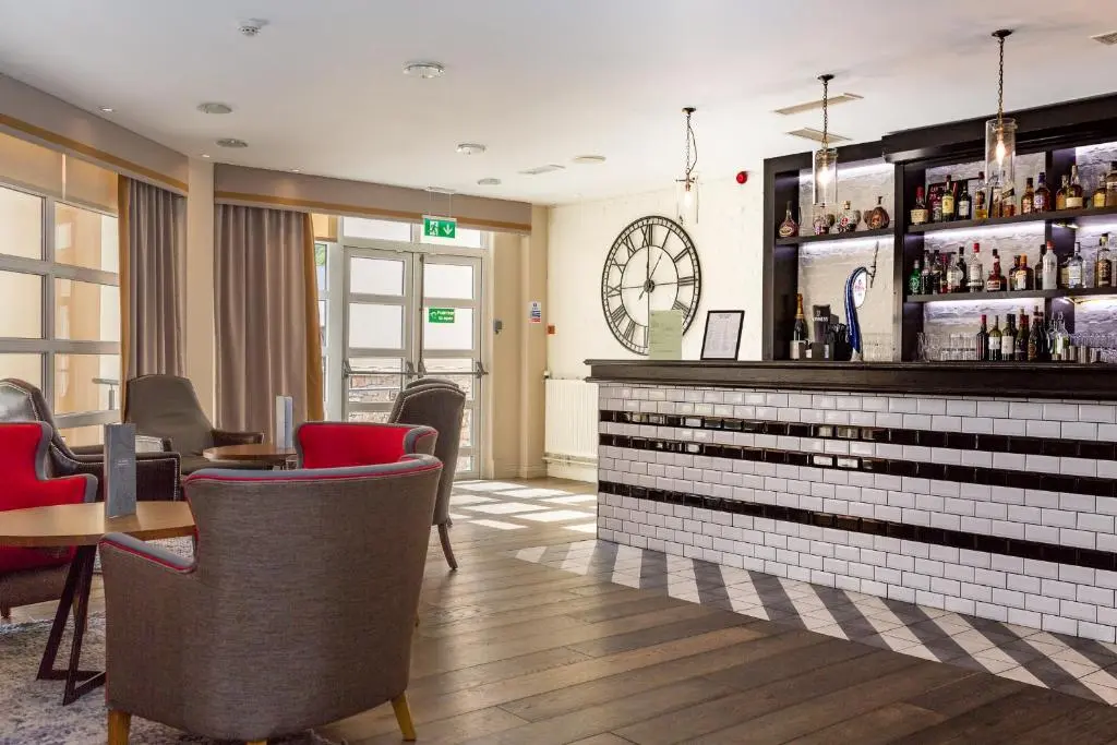 a restaurant with a bar with red chairs and tables at Macdonald Morlich Hotel at Macdonald Aviemore Resort in Aviemore