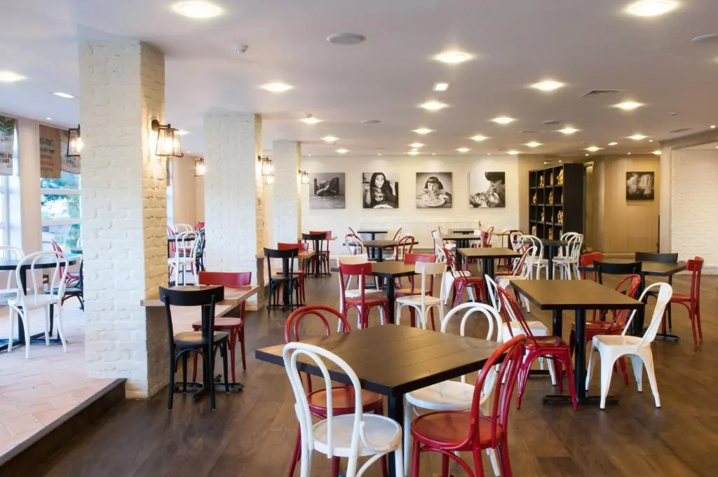 a restaurant with wooden tables and red chairs at Macdonald Morlich Hotel at Macdonald Aviemore Resort in Aviemore