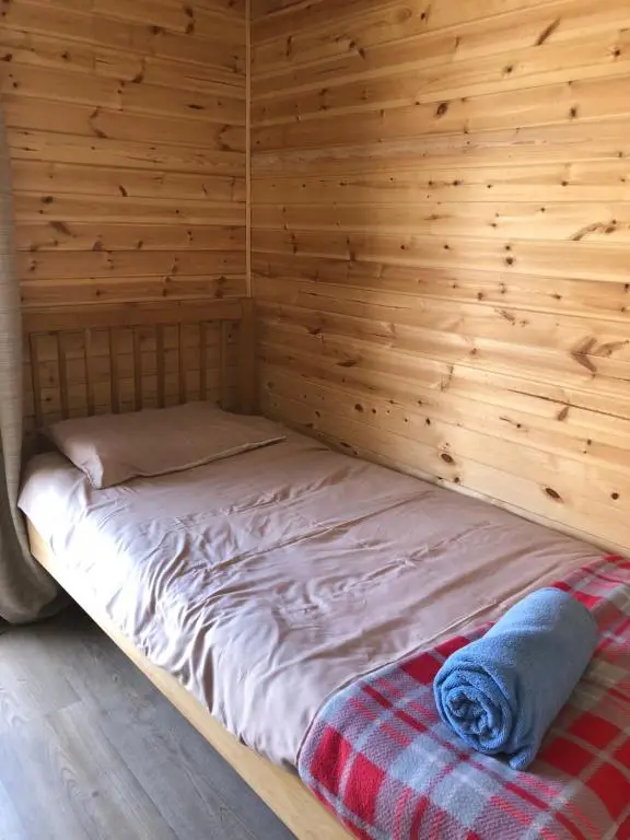 a bed in a room with a wooden wall at 1 Lochness Rooms&Hostel in Drumnadrochit