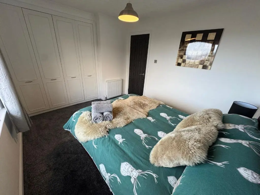 a bedroom with a bed with a green comforter at Firth View Heights in Inverness