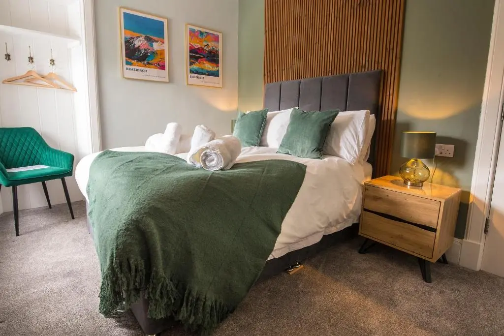 a bedroom with a large bed with a green blanket at The Braeriach in Newtonmore