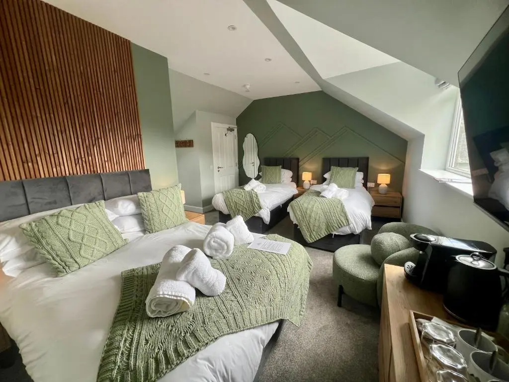 a hotel room with three beds with towels on them at The Braeriach in Newtonmore
