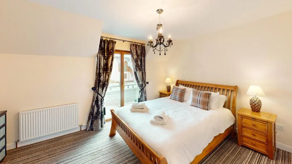 a bedroom with a large bed and a window at Lairig Ghru Lodge in Aviemore