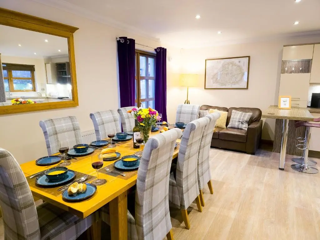 a dining room and living room with a table and chairs at Lairig Ghru Lodge in Aviemore