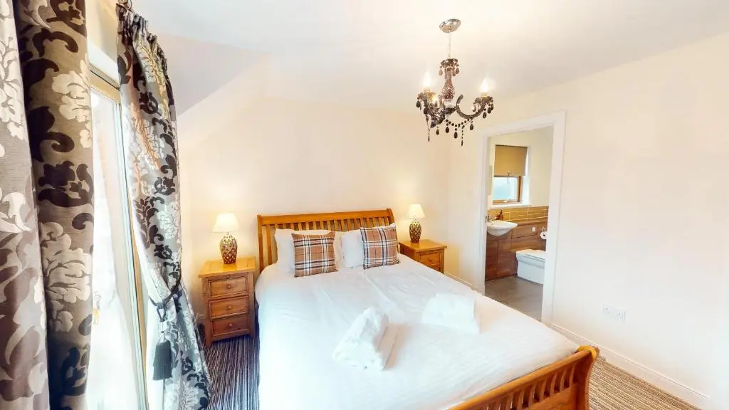 a bedroom with a bed and a chandelier at Lairig Ghru Lodge in Aviemore