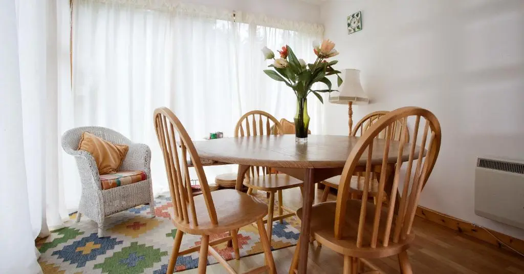 a dining room table with chairs and a vase of flowers at Heath Cottage, Tranquil Cottage by the Woods in Boat of Garten