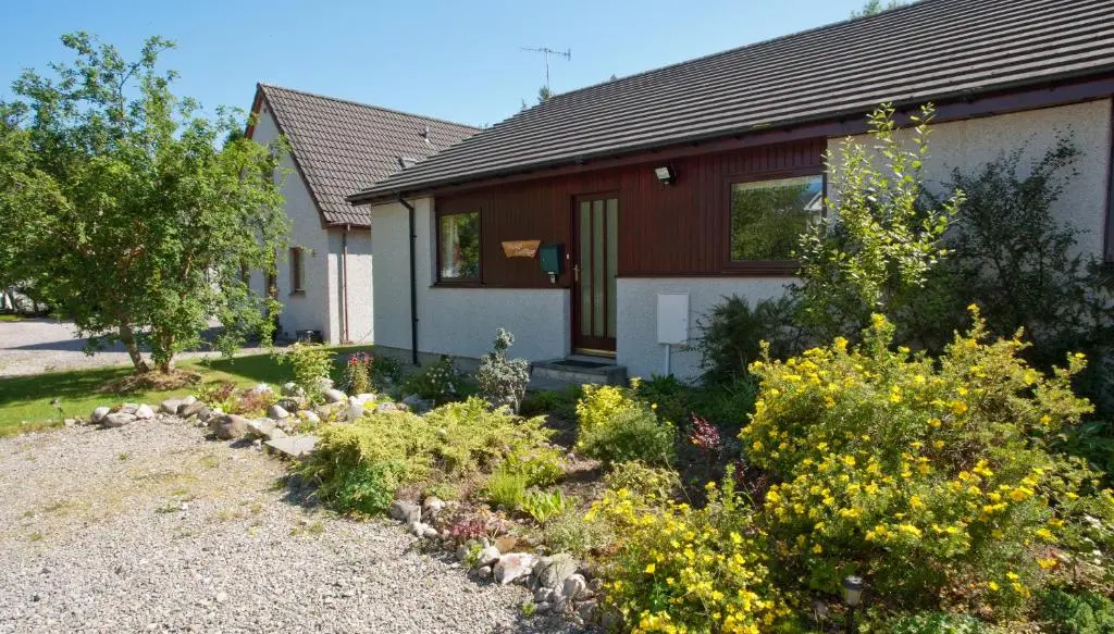 a house with a garden in front of it at Heath Cottage, Tranquil Cottage by the Woods in Boat of Garten