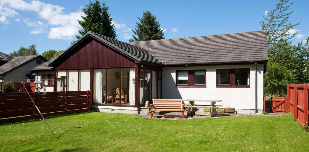 a house with a bench and a picnic table in the yard at Heath Cottage, Tranquil Cottage by the Woods in Boat of Garten