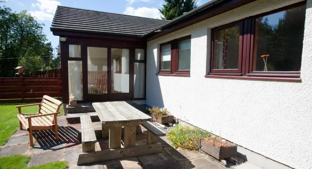 a picnic table and bench outside of a house at Heath Cottage, Tranquil Cottage by the Woods in Boat of Garten