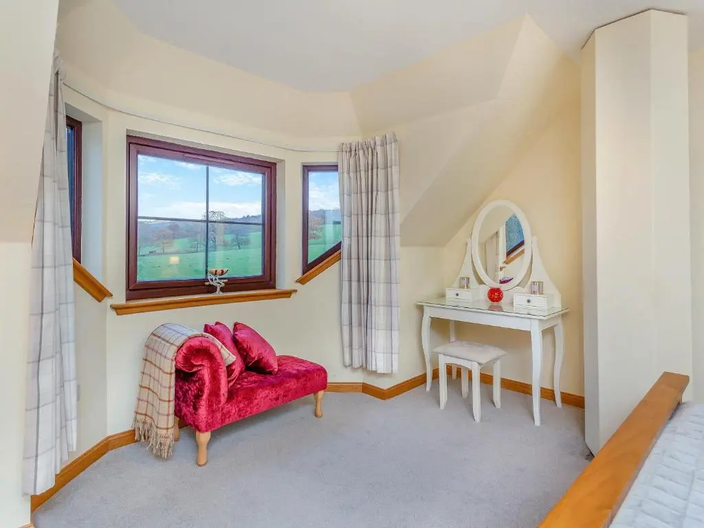 a living room with a red chair and a table at Bunchrew Farm Cottage in Inverness
