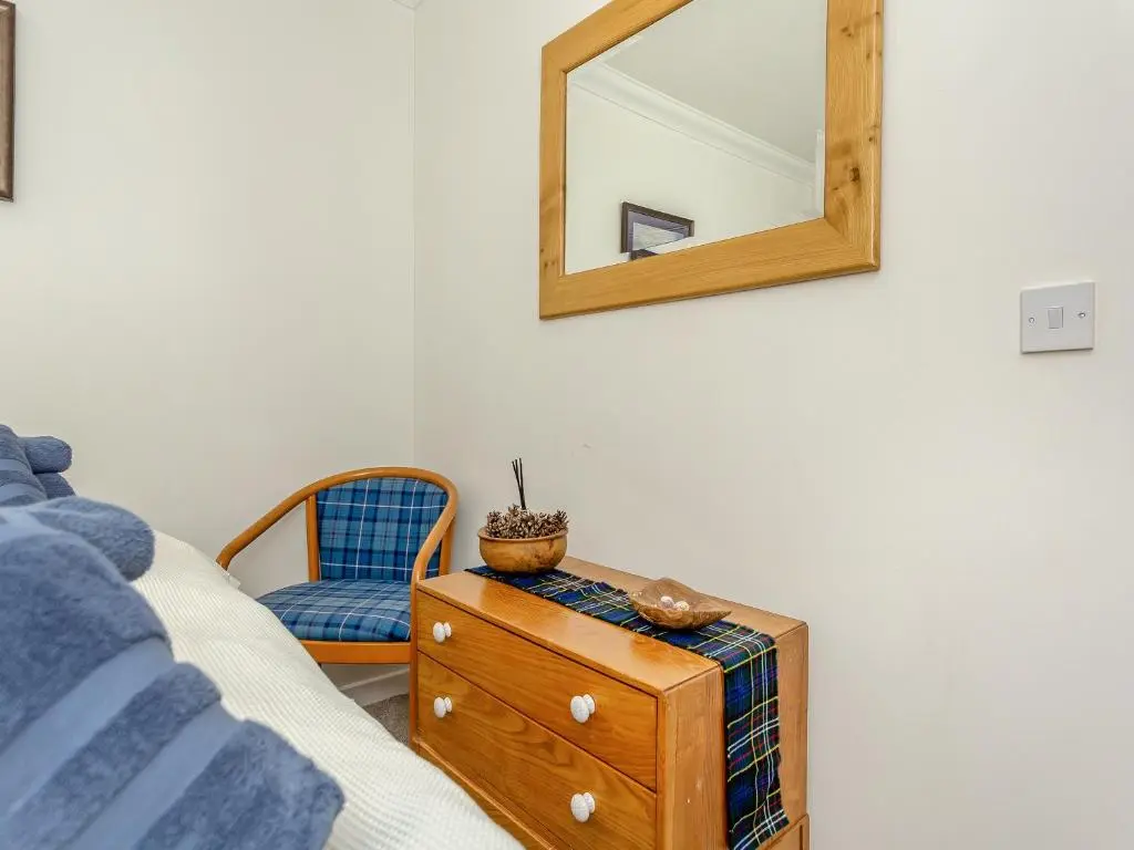 a mirror on a wall next to a bed and a chair at Rock Folly in Inverness