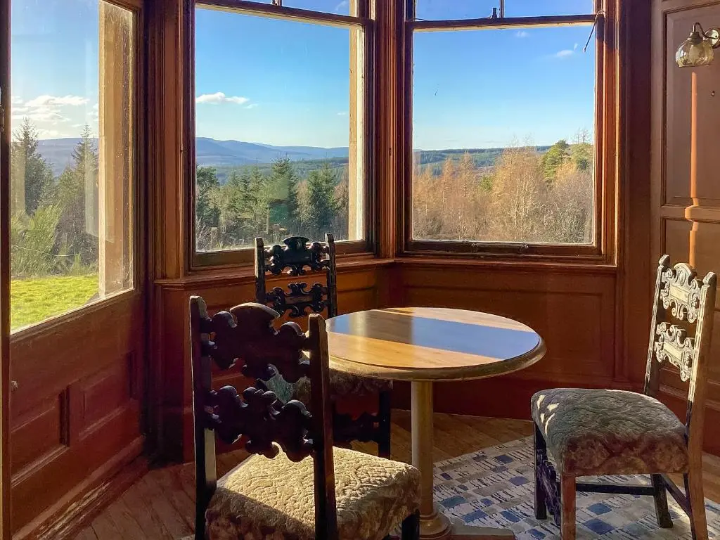 a room with a table and two chairs and windows at The Carnegie Rooms At Aultnagar Lodge - Uk48666 in Lairg