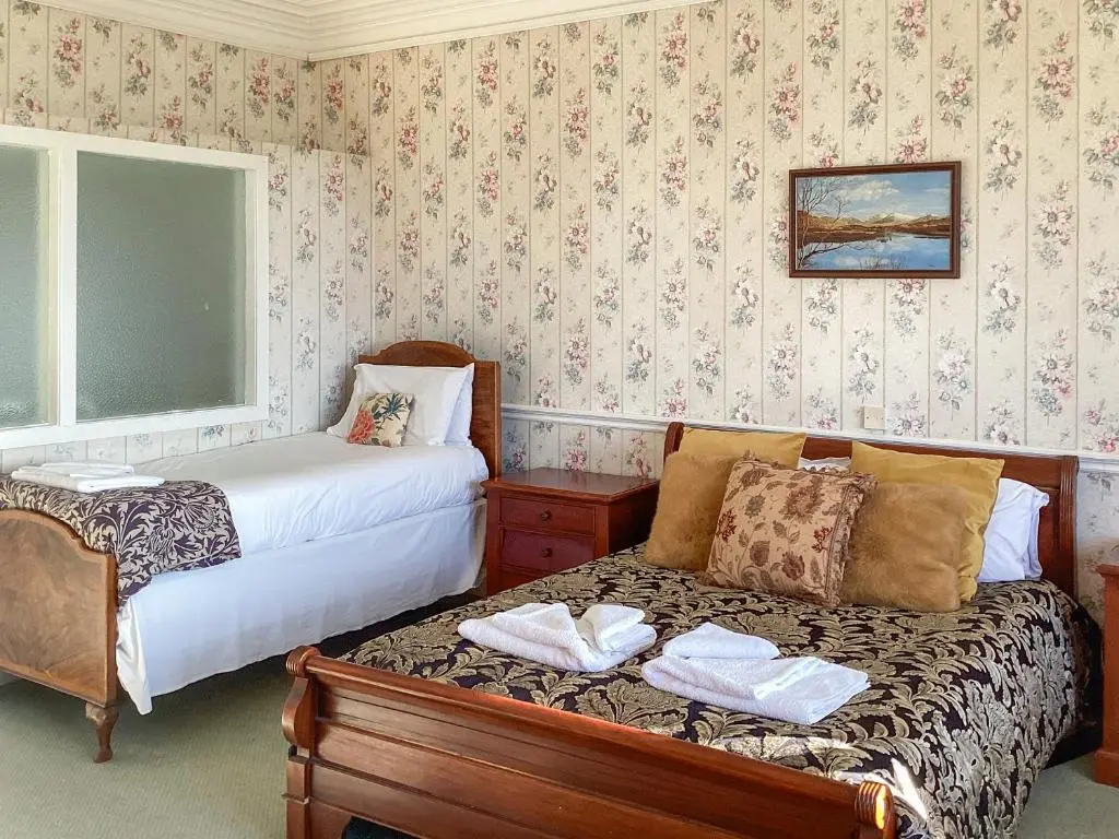 a bedroom with two beds and a bench with towels at The Carnegie Rooms At Aultnagar Lodge - Uk48666 in Lairg