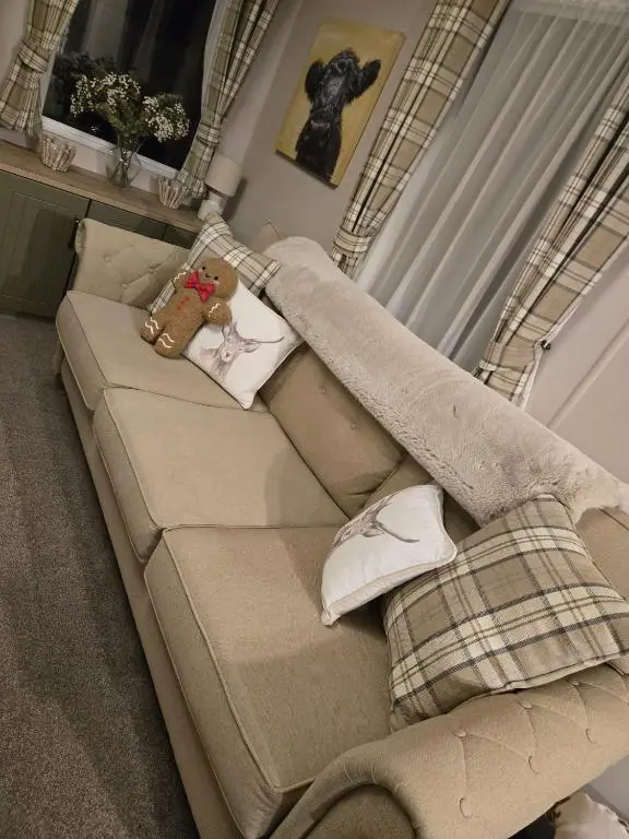 a brown couch with a teddy bear sitting on it at Lynmar retreat No 35 in Dornoch